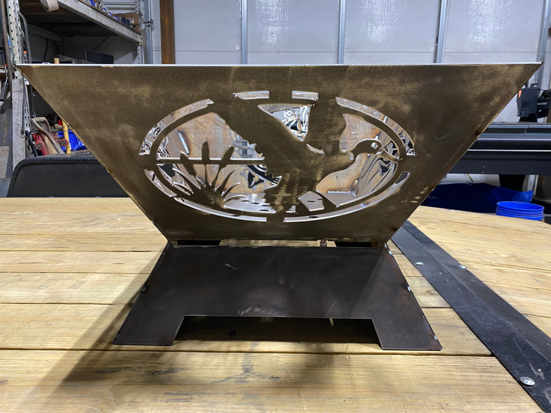 Custom steel fire pit with a waterfowl hunting scene cut-out on a welded base