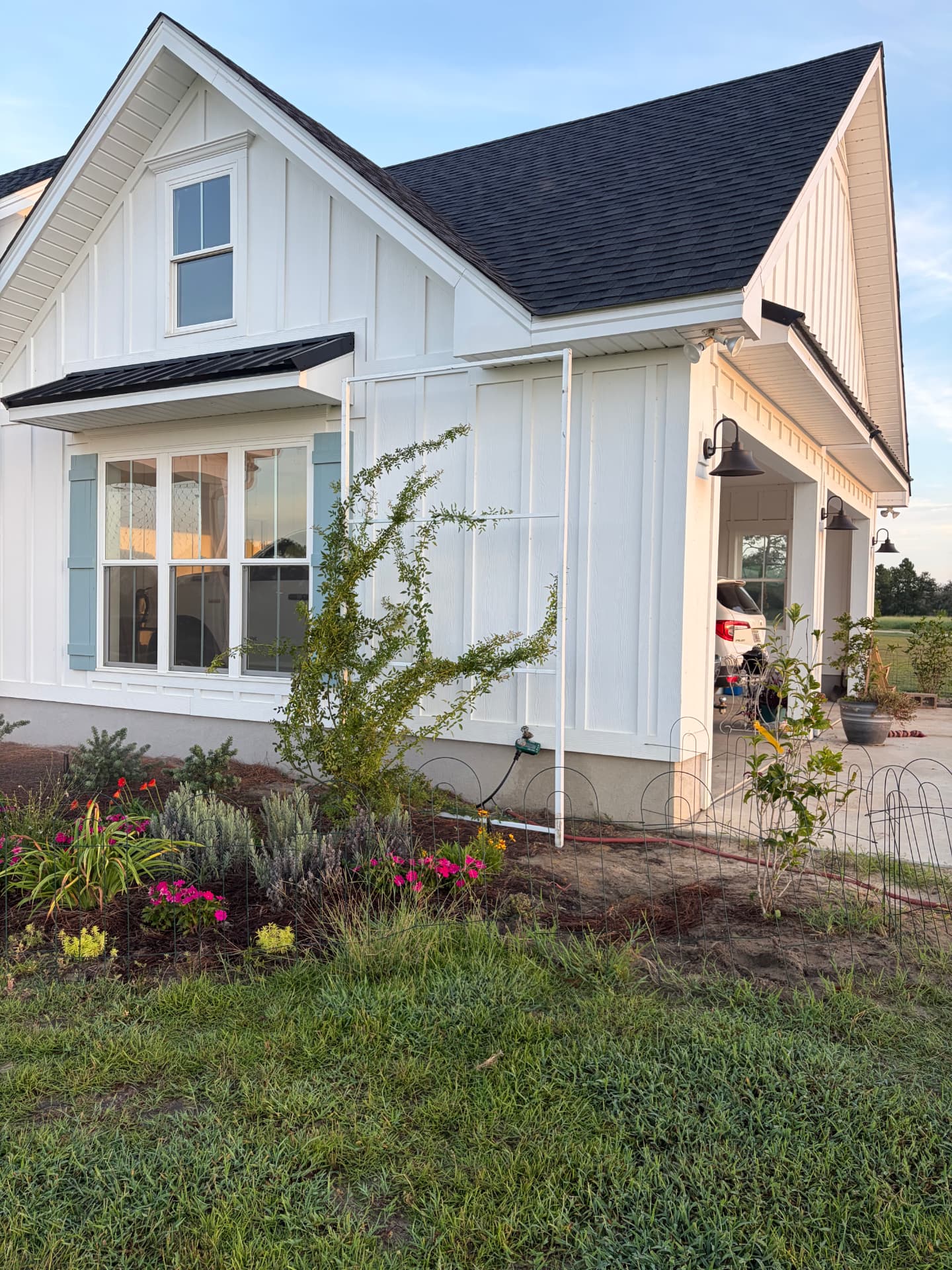 Custom steel rose trellis mounted on a white farmhouse wall